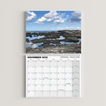 Calendar for November 2023 with a scenic view of rocks and water on a white background