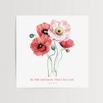 A square art print featuring a watercolor illustration of four poppies in shades of red, pink, and white with green stems, displayed on a light gray background. Below the flowers, the text reads 'Be Still And Know That I Am God' in a small red font.